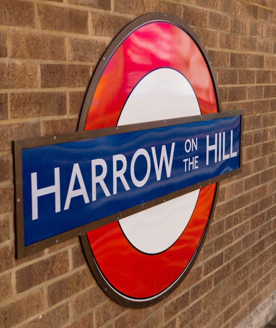 A circular London Underground sign featuring a red outer ring, a white central circle, and a blue rectangular station sign overlay with the text 'Harrow on the Hill' in white letters, mounted on a brown brick wall. The sign is illuminated by ambient lighting, and the brick wall has a textured appearance with evenly spaced mortar lines. The clean, polished surfaces and the neat appearance of the sign reflect a well-maintained environment, representative of professional surface cleaning and sanitisation services provided by Cleaner Harrow in Wealdstone and Headstone Lane Harrow.